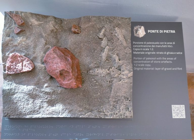 Pannello espositivo con la riproduzione di una porzione di paleosuolo contenente manufatti litici e relativo pannello descrittivo intitolato 'Ponte di Pietra'