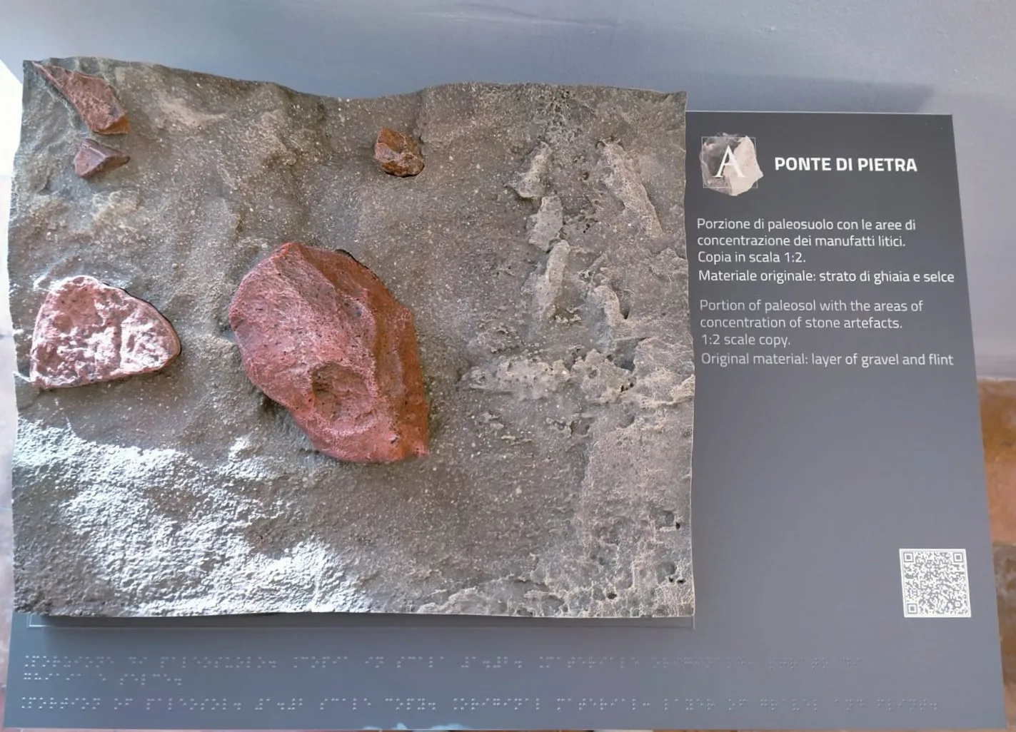 Pannello espositivo con la riproduzione di una porzione di paleosuolo contenente manufatti litici e relativo pannello descrittivo intitolato 'Ponte di Pietra'